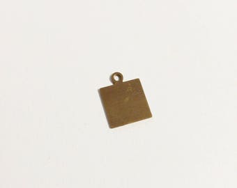 May include: A small, square, brass-colored charm with a loop at the top for attaching to a necklace or bracelet. The charm has a slightly aged appearance, suggesting it may be vintage or antique. The surface is smooth with subtle variations in color.