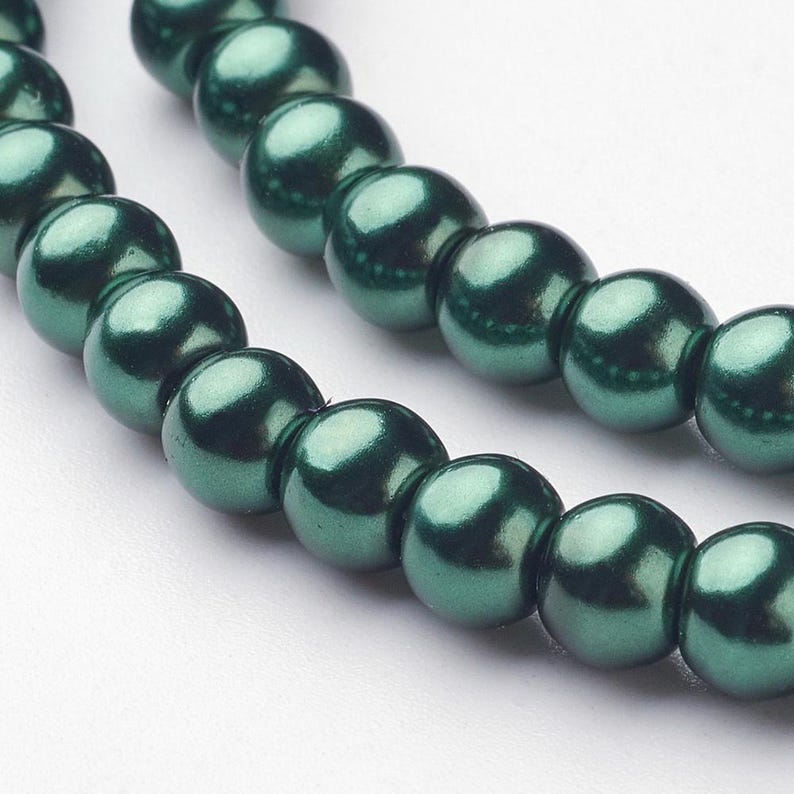 May include: A strand of dark green pearl beads. The beads are round and have a smooth, glossy finish.