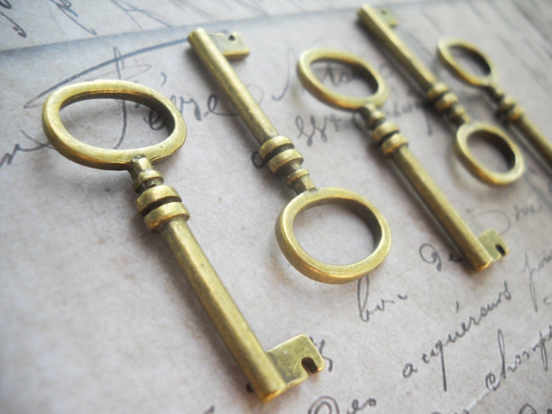 May include: Close-up of several antique-style brass keys. The keys have a vintage aesthetic, with a warm, golden hue. Each key features a distinct keyhole design and a decorative handle. The keys are arranged on a background with handwritten script.