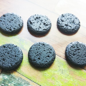 以下が含まれることがあります： ざらざらとした質感の黒い溶岩製の丸いコースターが6つあります