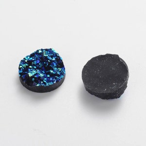 May include: Two round, flat, decorative cabochons. One is a dark blue with iridescent glitter, the other is black.