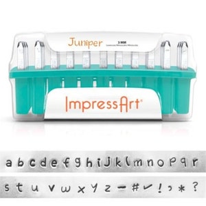 May include: A set of 3 mm metal letter stamps in a turquoise plastic case. The case has the text "Juniper" and "Impress Art" on it. The stamps include the alphabet, numbers, and punctuation marks.