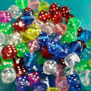 May include: A collection of colorful, translucent dice in various colors including red, green, blue, yellow, and purple. Each die has white dots indicating the numbers. The dice are scattered, creating a playful and vibrant display.