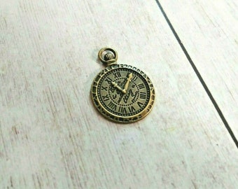 May include: A gold-toned pocket watch charm with Roman numeral markings on the face.