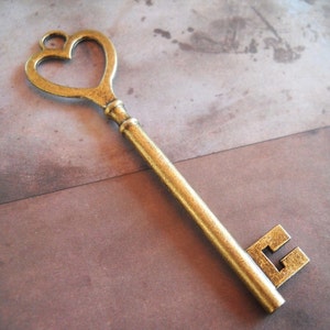 May include: An antique-style key with a heart-shaped top. The key is made of brass and has a detailed design. The key is a decorative item, perfect for crafts or as a unique accent piece. The key is approximately 6 inches long.