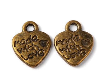 May include: Two gold-tone metal heart-shaped charms with the words "Made with Love" engraved on them. Each charm has a small loop at the top for attaching to a necklace or bracelet.