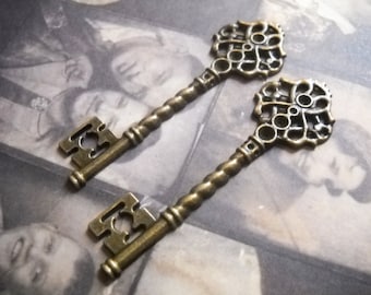 May include: Two antique-style skeleton keys with ornate, filigree-like heads. The keys are made of a brass-coloured metal and have a twisted, spiral-shaped shaft.