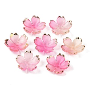 Pode incluir: Oito enfeites de resina em forma de flor de cerejeira rosa e dourado. As flores têm um degradado de rosa de rosa claro a rosa escuro.