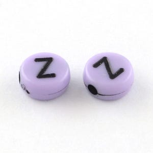 K&ouml;nnte beinhalten: Zwei lila Buchstabenperlen mit dem Buchstaben "Z" in Schwarz auf jeder Perle.