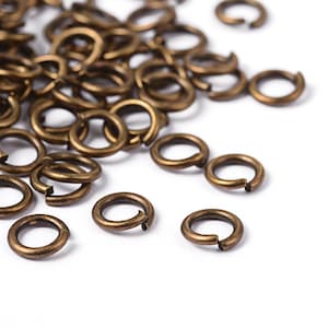 May include: A pile of antique brass jump rings, a type of metal ring used in jewelry making.