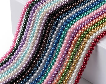 May include: A selection of colourful beaded necklaces in shades of pink, green, purple, and blue. The small, round beads are strung together to form strands. The necklaces are arranged diagonally, displaying the variety of colours available.
