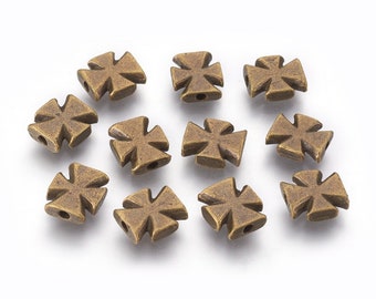 May include: Twelve antique gold-toned metal cross-shaped beads. The beads are square-shaped with a raised cross design.
