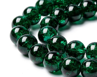 May include: A strand of dark green glass beads with a crackled finish. The beads are round and have a glossy sheen.