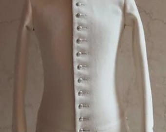 May include: A white jacket with a high collar and long sleeves, featuring a row of silver buttons down the front. The collar and cuffs are trimmed with navy blue fabric. The jacket is displayed on a mannequin.