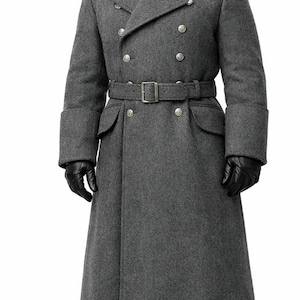Puede incluir: Un abrigo militar gris de lana con diseño cruzado, botones plateados, cinturón en la cintura y guantes de cuero negro. El abrigo tiene cuello alto y se combina con una gorra militar a juego.