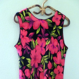 May include: A sleeveless top with a black background and a floral print featuring pink and green flowers.