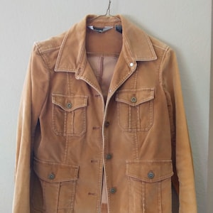May include: A brown corduroy jacket with a button-up front and multiple pockets. The jacket has a slightly faded look.