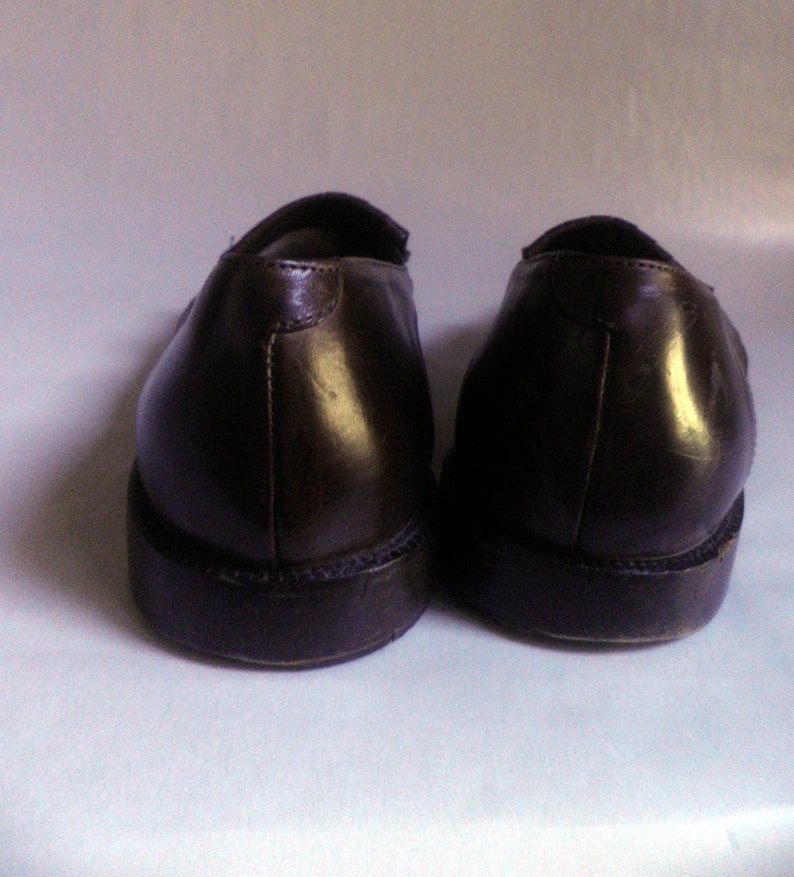 Puede incluir: Un par de mocasines de cuero marr&oacute;n con punta ligeramente puntiaguda. Los zapatos tienen una suela marr&oacute;n oscura y una parte superior de cuero liso.