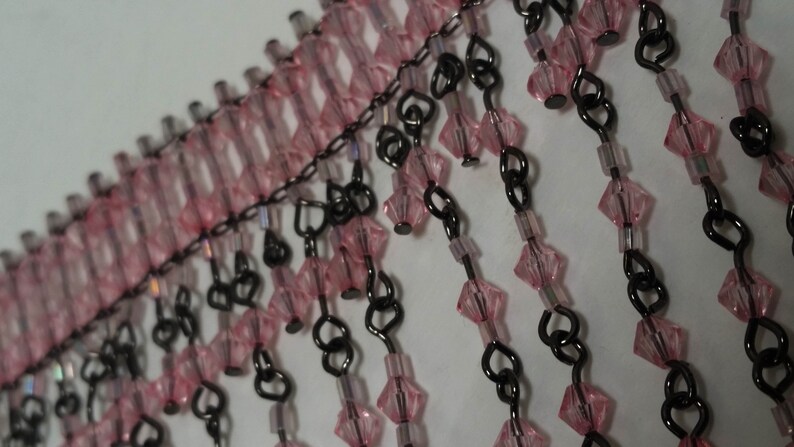 Pode incluir: Franja de contas rosa e preta com uma corrente e elos em forma de cora&ccedil;&atilde;o. A franja &eacute; feita de pequenas contas facetadas.