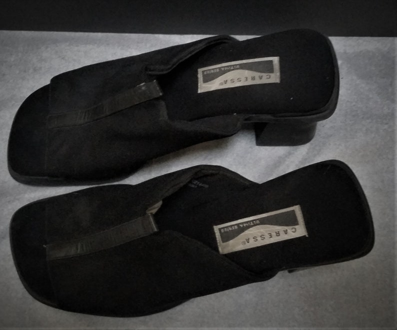 Puede incluir: Un par de sandalias negras de tac&oacute;n con una tira sobre el dedo del pie. Las sandalias tienen una etiqueta que dice "CARESSAR, STYLISH SERIES".