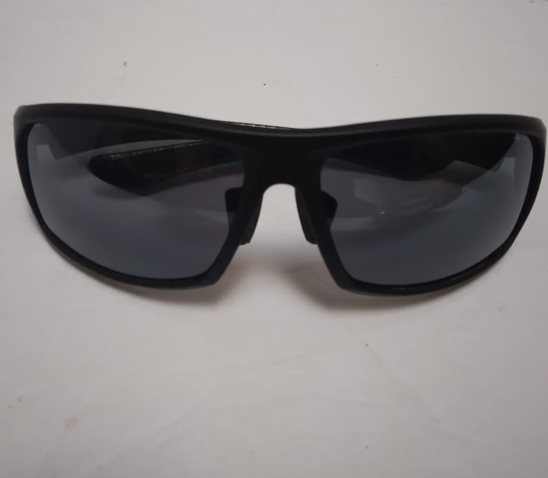 May include: Black sunglasses with dark gray lenses. The sunglasses have a curved, sporty design with a thick frame. The lenses are reflective, and the overall look is sleek and modern. Suitable for outdoor activities.