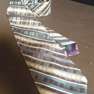 May include: A striped tie with a brown, beige, green, and white pattern. The tie has a small tag that says "100% Polyester Made in Korea".