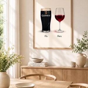 May include: A framed print featuring a pint of Guinness and a glass of red wine, labeled "His" and "Hers." The Guinness glass is black with a white head, and the wine glass is filled with red wine. The print is displayed in a dining room setting.
