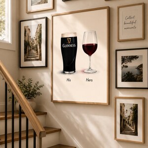 May include: A framed print featuring a pint of Guinness and a glass of red wine, labeled "His" and "Hers." The artwork is surrounded by other framed pictures, including coastal scenes and botanical prints. The image is displayed on a wall next to a staircase.