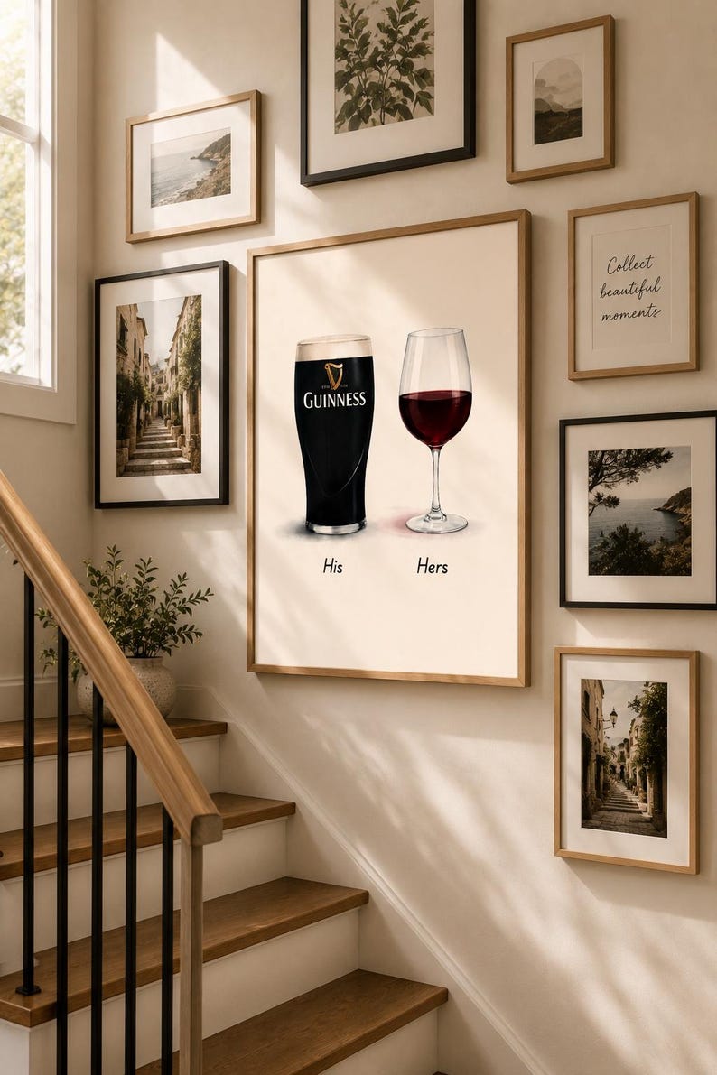 May include: A framed print featuring a pint of Guinness and a glass of red wine, labeled "His" and "Hers." The artwork is surrounded by other framed pictures, including coastal scenes and botanical prints. The image is displayed on a wall next to a staircase.