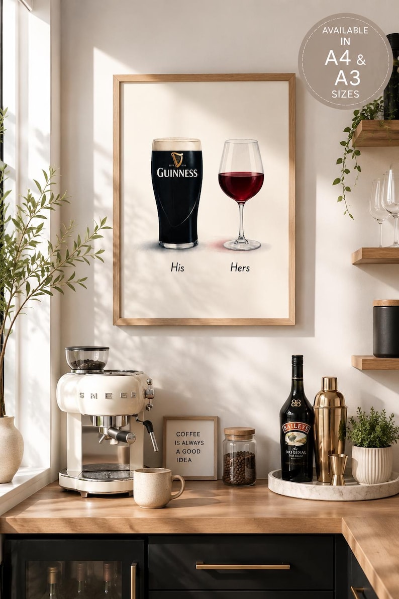 May include: A framed print featuring a pint of Guinness and a glass of red wine, labeled "His" and "Hers." The print is displayed above a countertop with a coffee machine, a bottle of Bailey's, and a sign that reads "COFFEE IS ALWAYS A GOOD IDEA."