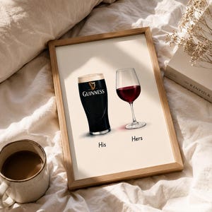 May include: A framed print featuring a pint of Guinness and a glass of red wine, labeled "His" and "Hers". The Guinness glass is black with a white head, and the wine glass is filled with red wine. The print is in a wooden frame.