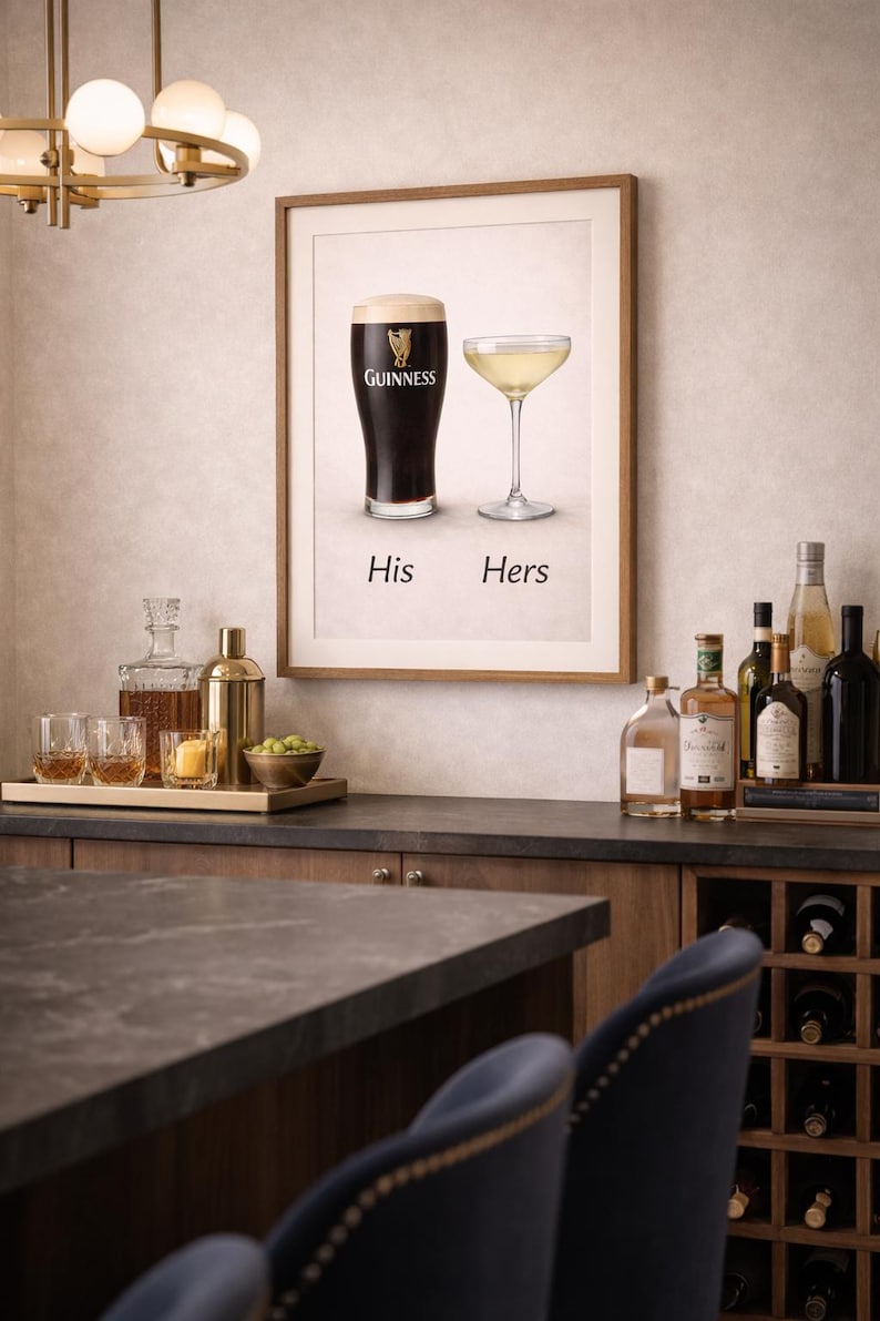 Może przedstawiać: Oprawiony wydruk przedstawiający kufel Guinnessa i kieliszek do szampana z napisem "His Hers". Obraz wyświetlany jest nad barem z butelkami alkoholi i win. Na barze znajduje się taca ze szklankami i shakerem do koktajli.