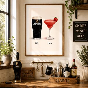 May include: A framed print featuring a pint of Guinness and a strawberry margarita, labeled "His" and "Hers." The image is set in a kitchen with bar accessories, including a Guinness tap, bottles, and a sign that reads "Spirits Wines Ales."