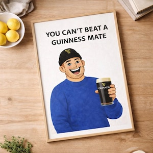 Peut inclure: Impression encadr&eacute;e avec l'inscription &laquo; YOU CAN'T BEAT A GUINNESS MATE &raquo; au-dessus d'une illustration d'un homme en pull bleu et bonnet noir tenant une pinte de Guinness. L'image est pos&eacute;e sur un fond en bois.