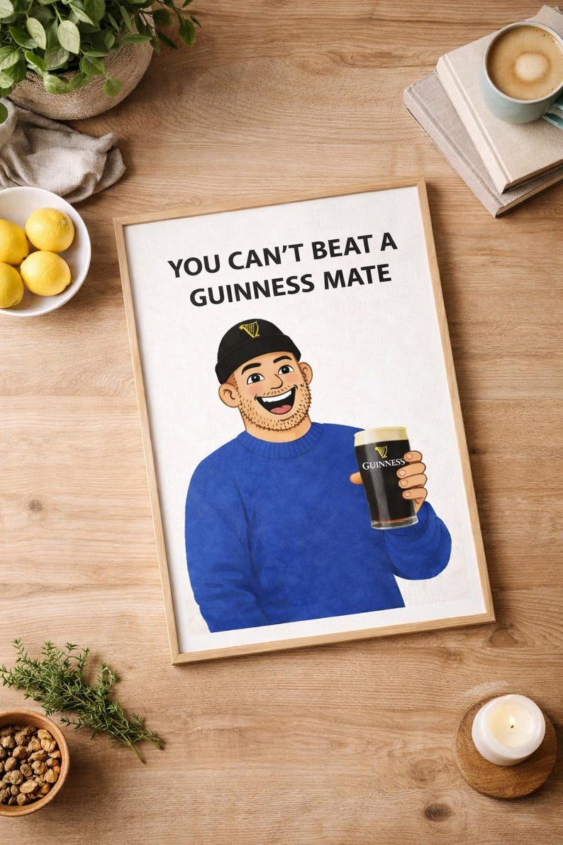Peut inclure: Impression encadr&eacute;e avec l'inscription &laquo; YOU CAN'T BEAT A GUINNESS MATE &raquo; au-dessus d'une illustration d'un homme en pull bleu et bonnet noir tenant une pinte de Guinness. L'image est pos&eacute;e sur un fond en bois.