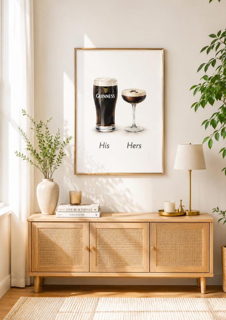 Puede incluir: Impresi&oacute;n enmarcada con dos bebidas: una pinta de Guinness y un c&oacute;ctel. Las palabras "His" y "Hers" est&aacute;n debajo. La impresi&oacute;n cuelga sobre un mueble de madera clara con puertas de ca&ntilde;a tejida, una l&aacute;mpara y objetos decorativos.