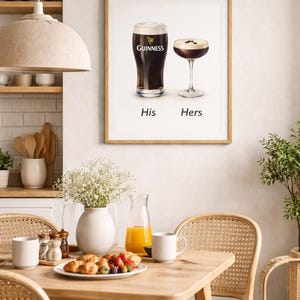 Puede incluir: Un cuadro enmarcado con una pinta de Guinness y un c&oacute;ctel, etiquetados como "His" y "Hers". La imagen est&aacute; ambientada en un comedor con una mesa de madera, sillas y un jarr&oacute;n con flores. En la mesa hay un plato con comida y bebidas.