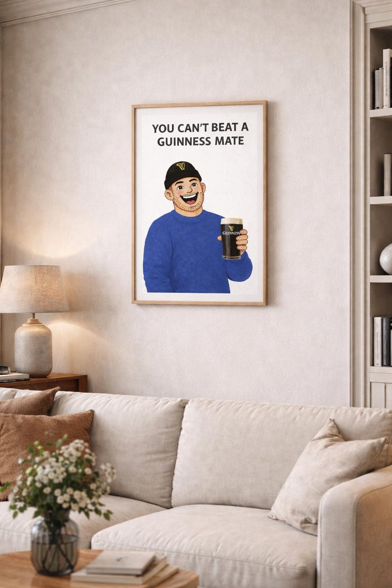Peut inclure: Impression encadr&eacute;e avec une illustration de dessin anim&eacute; d'une personne tenant une pinte de Guinness. La personne porte un pull bleu et un bonnet noir. Le texte "YOU CAN'T BEAT A GUINNESS MATE" est affich&eacute; au-dessus de l'illustration. L'&oelig;uvre est expos&eacute;e dans un salon.
