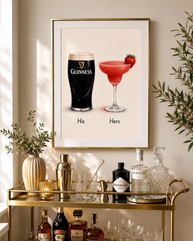 May include: A framed print featuring a pint of Guinness and a strawberry margarita, labeled "His" and "Hers." The print is displayed above a gold bar cart with bottles of liquor, glassware, and bar tools. The overall theme is home bar decor.