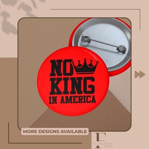 Könnte beinhalten: Ein roter Button mit dem schwarzen Text "NO KING IN AMERICA", gekrönt von einer schwarzen Krone. Der Button hat eine Metallnadel auf der Rückseite. Das Bild zeigt auch einen zweiten Button und den Text "MORE DESIGNS AVAILABLE".