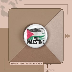Puede incluir: Un botón redondo con el diseño de la bandera palestina, con colores rojo, blanco, negro y verde, y la inscripción "FREE PALESTINE". El botón está sobre un fondo marrón y beige, con el texto "MORE DESIGNS AVAILABLE".