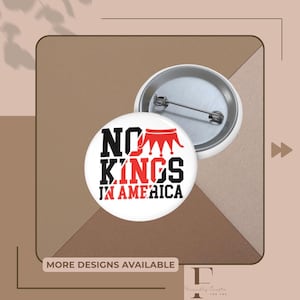 Könnte beinhalten: Weißer Button mit dem Text "NO KINGS IN AMERICA" in Schwarz und Rot. Der Button hat eine rote Kronengrafik. Ein zweiter Button zeigt die Nadelrückseite. Der Hintergrund ist braun und beige.