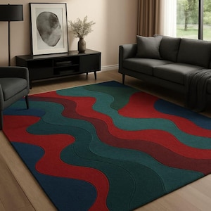 Peut inclure: Un tapis de sol coloré avec un motif ondulé dans les tons de rouge, vert d'eau et bleu. Le tapis est rectangulaire et posé sur un parquet. La pièce comprend également un meuble TV noir, un canapé gris et un lampadaire noir.