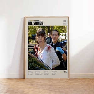 Può includere: Un poster cinematografico incorniciato per "The Sinner" con una donna con una camicia bianca macchiata di sangue che viene arrestata da un agente di polizia. Il poster include il titolo, il cast e l'anno 2017.
