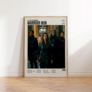 Puede incluir: Un póster enmarcado de la serie "Warrior Nun" con un grupo de mujeres vestidas de oscuro. El título está en la parte superior, con el año 2020 en la parte inferior. El póster está en una pared blanca sobre un suelo de madera.