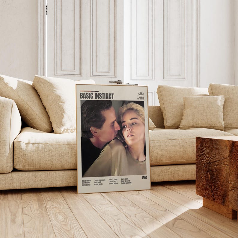May include: A framed movie poster for "Basic Instinct" featuring Michael Douglas and Sharon Stone. The poster has a beige background with the film's title at the top and the year 1992 at the bottom. The image shows the actors in a close embrace.