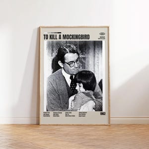 Peut inclure: Affiche encadrée du film "To Kill a Mockingbird" avec une image en noir et blanc d'un homme et d'un enfant. L'affiche comprend le titre du film, le nom du réalisateur et l'année 1962. L'affiche est affichée sur un mur de couleur claire.
