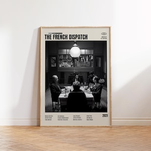 May include: A framed black and white poster for "The French Dispatch" film. The poster features a scene of people seated around a table. The film title and cast names are displayed at the top and bottom of the poster, with the year 2021 on the right.