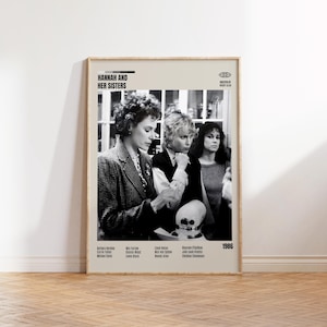 Puede incluir: Un póster de película en blanco y negro enmarcado para "Hannah y sus hermanas" con tres mujeres. El póster incluye el título de la película, el elenco y el año 1986. El póster se muestra en una pared clara.