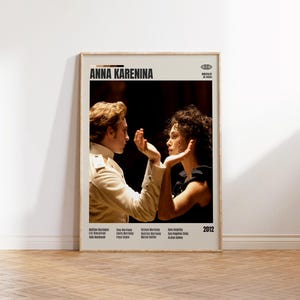 May include: A framed poster for the film "Anna Karenina" featuring two actors in costume. The poster has a beige background with the title in bold black letters. The year 2012 is printed in the bottom right corner.